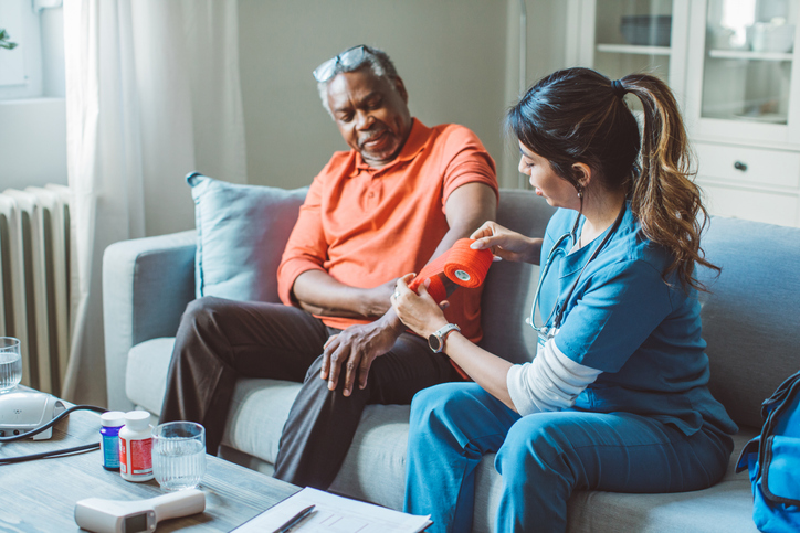 Caregiver helping patient dress wound.